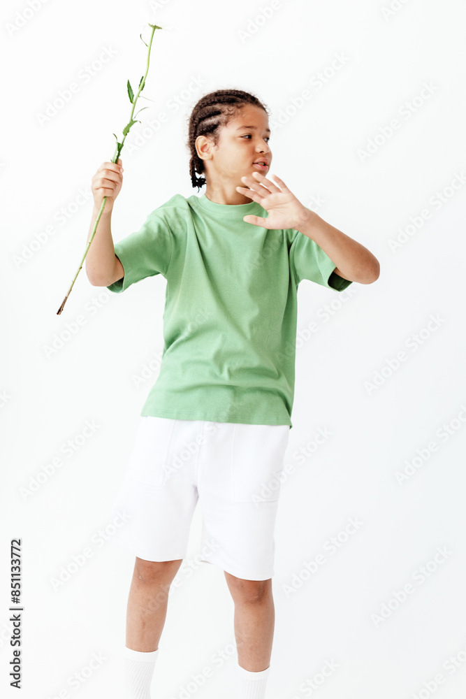 Young boy in green shirt and white shorts holds plant with care in trendy garden setting Young boy in green shirt and white shorts holds plant with care in trendy garden setting