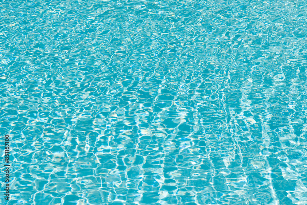 Obraz premium Pool side resort with pool water surface background. Sea ripples on blue pool background. Sea background. Swimming pool rippled. Summer vacation. Spa resort on summer vacation. Caribbean sea