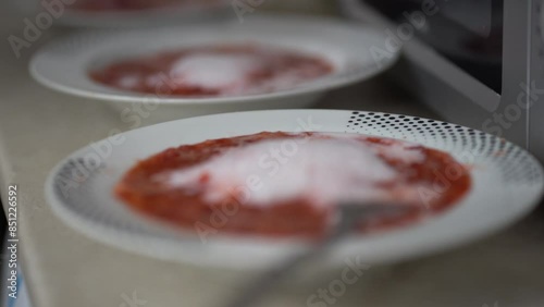 Homemade dessert. A man's hand with a spoon, mix strawberry puree with milk in a plate. Milk foam in a bowl on strawberries. High quality 4k footage photo