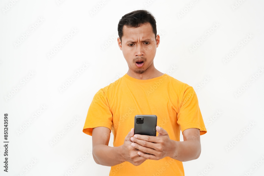 a young man wearing a yellow t-shirt was surprised to see a cellphone. With a plain white background a young man wearing a yellow t-shirt was surprised to see a cellphone. With a plain white background