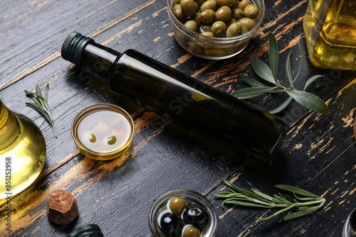 Different glassware with fresh olive oil on black wooden background