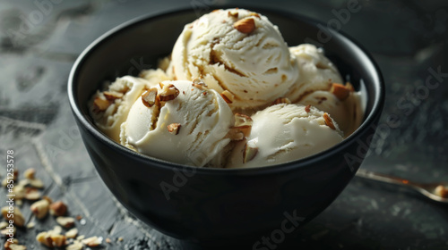 vanilla ice cream with almond pieces in a black bowl on a dark background