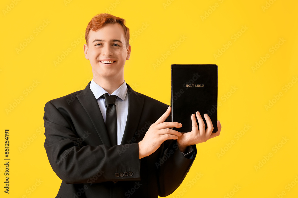 Young redhead man with Bible on yellow background Young redhead man with Bible on yellow background