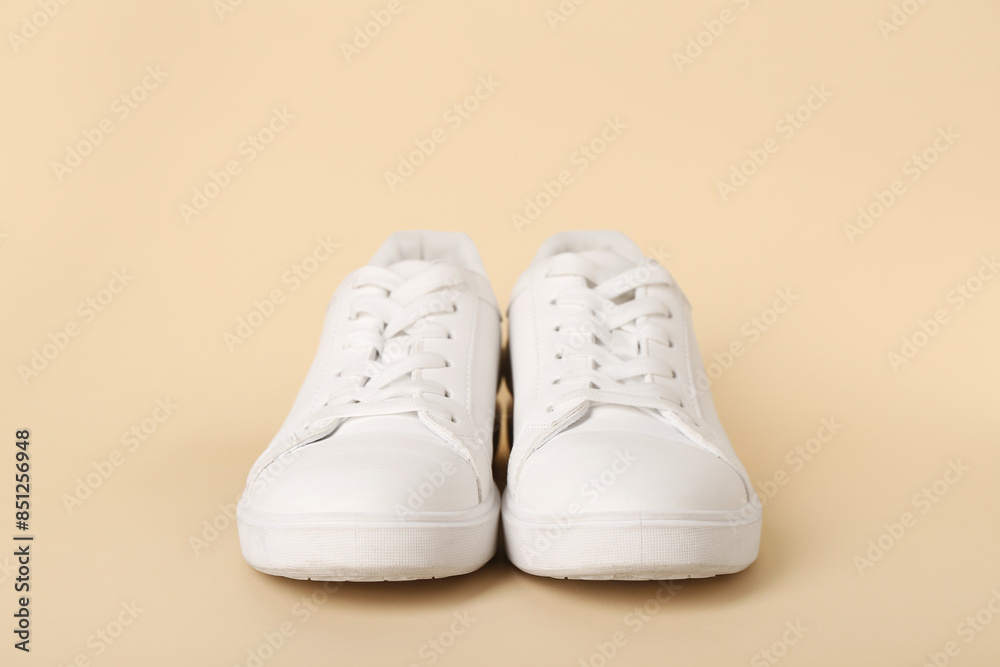 Stylish white sneakers on beige background Stylish white sneakers on beige background