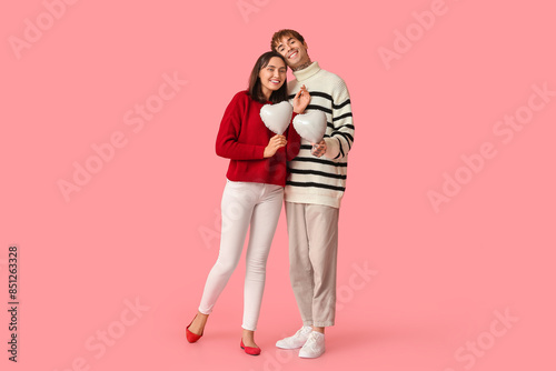 Young couple with air balloons in shape of heart on pink background. Valentine's Day celebration © Pixel-Shot