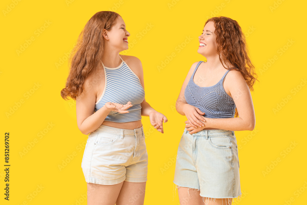 Happy redhead sisters on yellow background Happy redhead sisters on yellow background