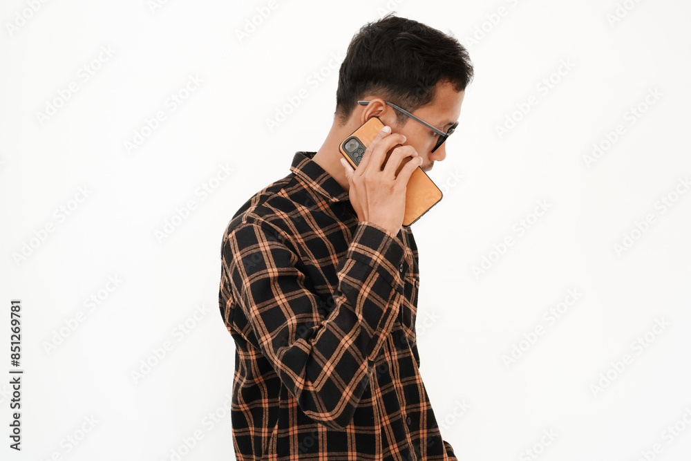 a young man wearing a flannel shirt, wearing glasses is making a telephone call. With a plain white background a young man wearing a flannel shirt, wearing glasses is making a telephone call. With a plain white background