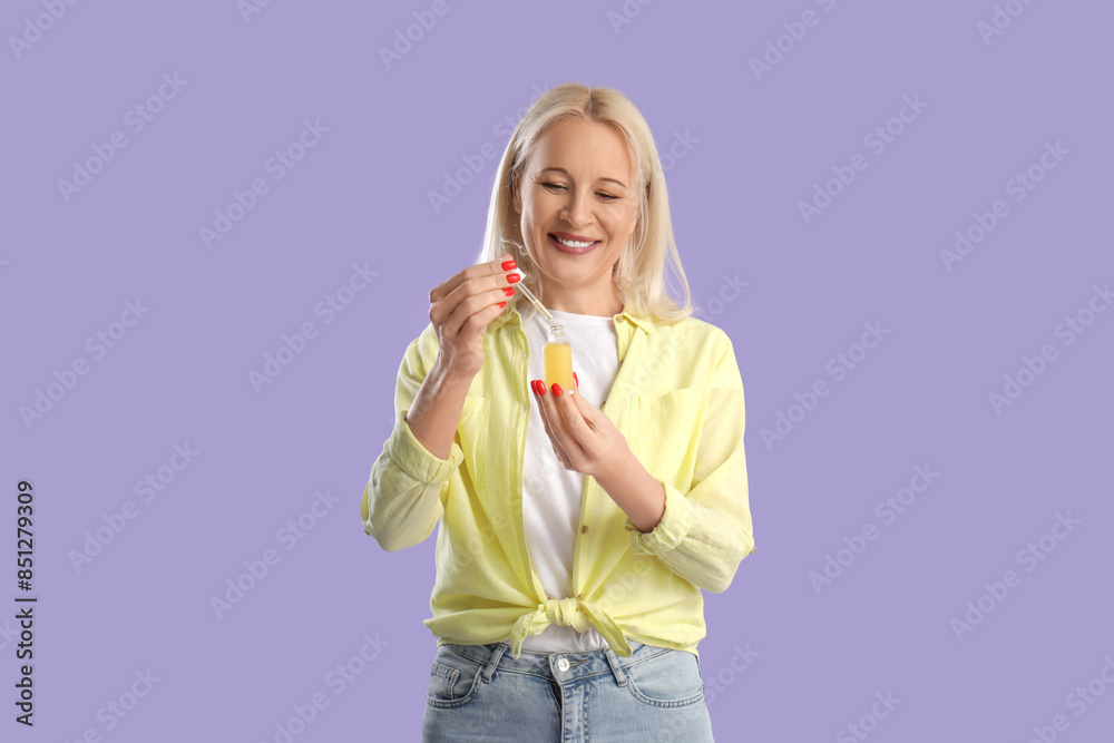 Mature woman with bottle of CBD oil on lilac background Mature woman with bottle of CBD oil on lilac background