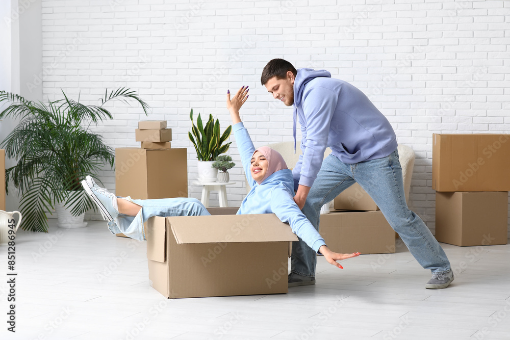 Young happy Muslim couple with belongings in their new house
