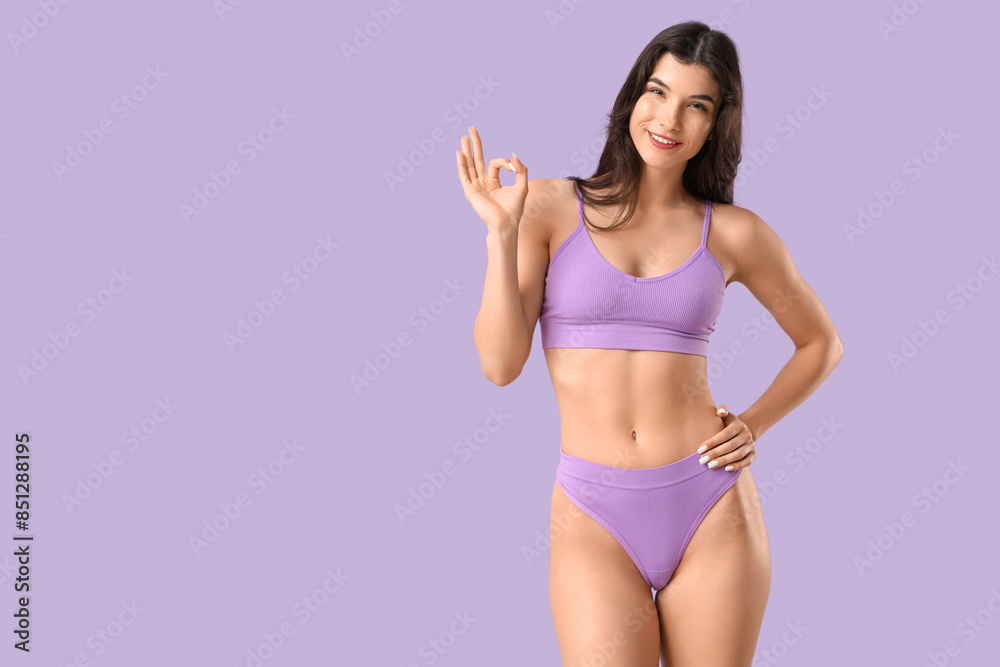 Pretty young woman in underwear showing OK on lilac background Pretty young woman in underwear showing OK on lilac background