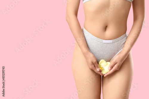 Young woman in panties with beautiful yellow orchid flower on pink background