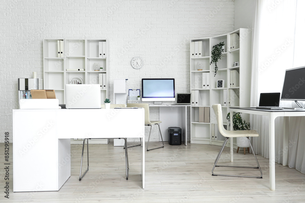 Interior of light office with modern workplaces and shelf units Interior of light office with modern workplaces and shelf units