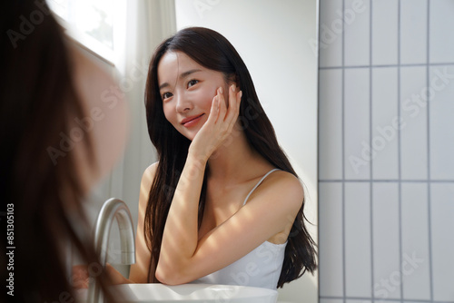鏡の前でスキンケアをする若いアジア人女性