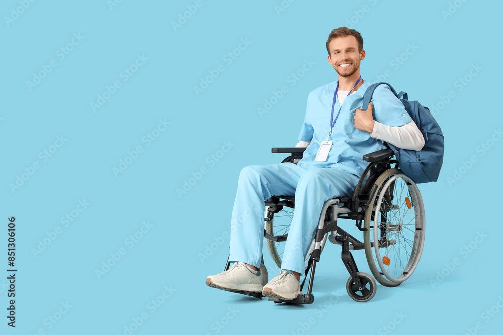 Male medical intern in wheelchair with backpack on blue background Male medical intern in wheelchair with backpack on blue background
