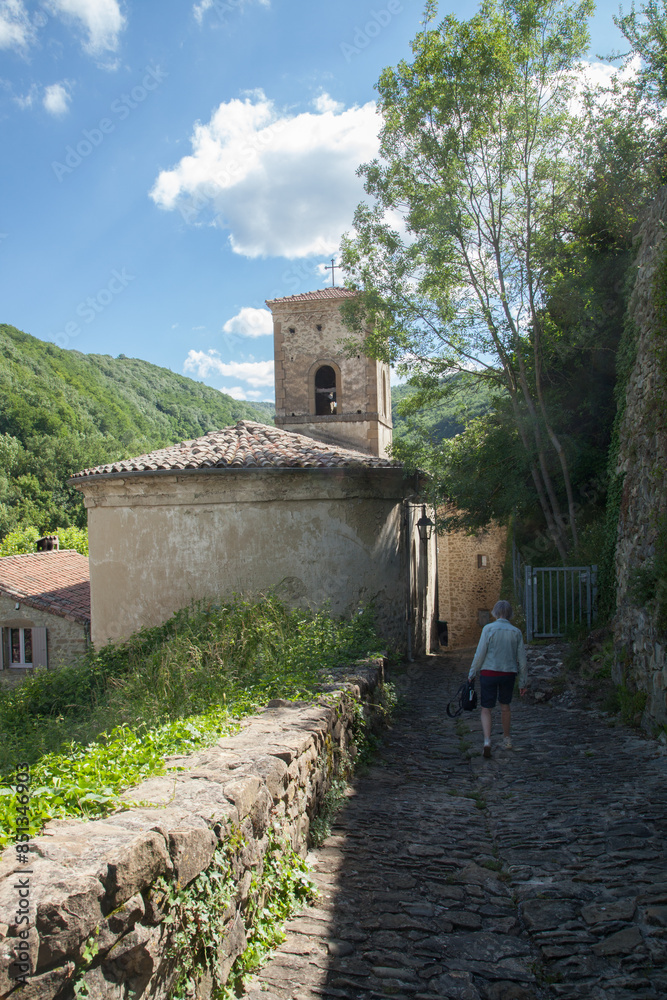 Femme touriste descendant une ruelle pavée du village médiéval du Poët-Célard (Drôme) Femme touriste descendant une ruelle pavée du village médiéval du Poët-Célard (Drôme)