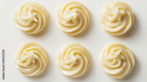 Five decorative twirls of creamy mayonnaise over a white background viewed from above for food styling concepts.