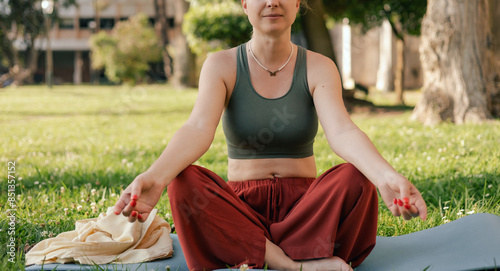 Middle aged woman practicing breathing yoga pranayama outdoors. Yoga instructor doing yoga exercise in the park, sport yoga concept. Unity with nature concept