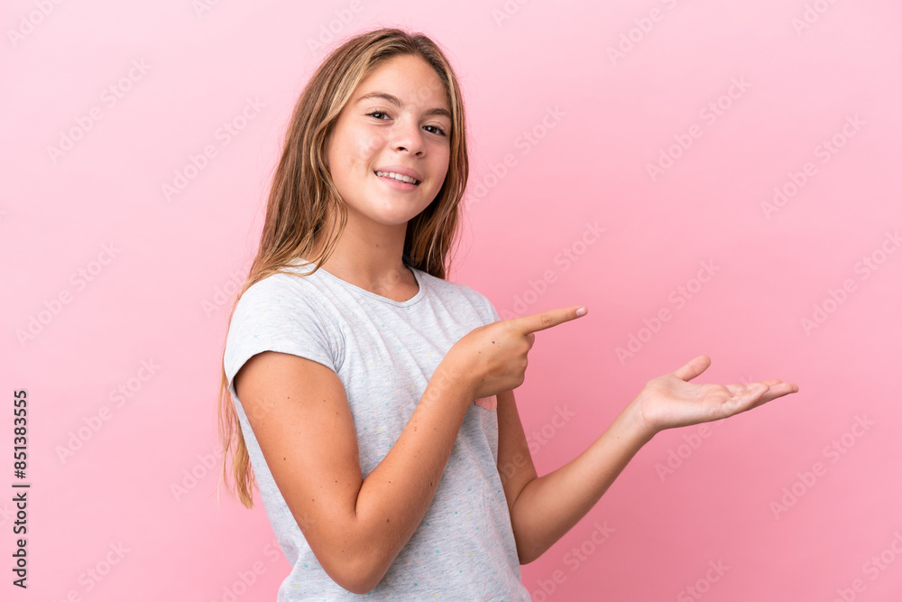 Little caucasian girl isolated on pink background holding copyspace imaginary on the palm to insert an ad Little caucasian girl isolated on pink background holding copyspace imaginary on the palm to insert an ad