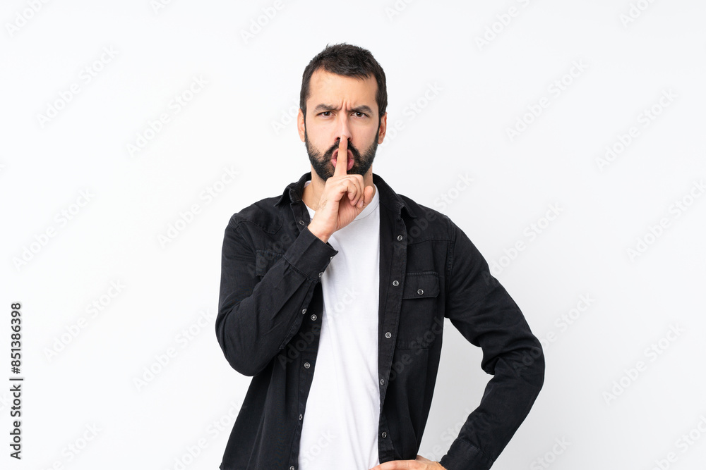 Young man with beard over isolated white background showing a sign of silence gesture putting finger in mouth Young man with beard over isolated white background showing a sign of silence gesture putting finger in mouth