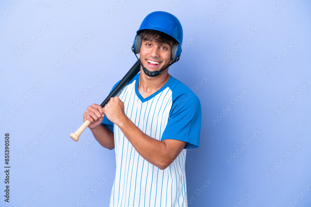 Baseball caucasian man player with helmet and bat isolated on blue background celebrating a victory Baseball caucasian man player with helmet and bat isolated on blue background celebrating a victory