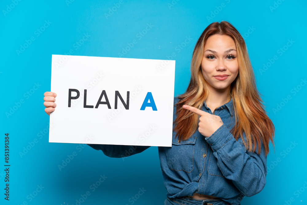 Teenager girl over isolated blue background holding a placard with the message PLAN A and pointing it Teenager girl over isolated blue background holding a placard with the message PLAN A and pointing it