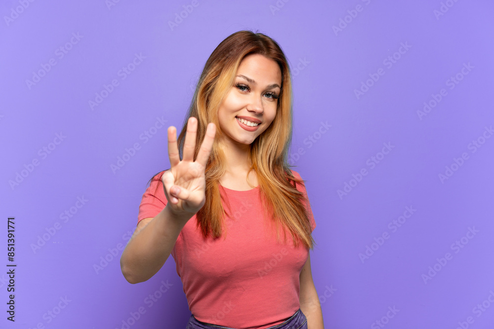 Fototapeta premium Teenager girl over isolated purple background happy and counting three with fingers