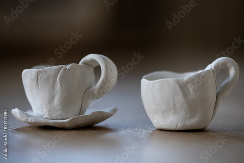 Close-up on two small coffee cups made of clay. Homemade clay objects.