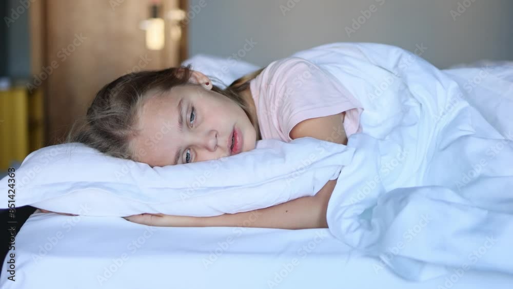 Portrait of a cute little girl lying on a cozy white pillow and under a blanket on her beautiful bed. The concept of daytime sleep and relaxation for children Portrait of a cute little girl lying on a cozy white pillow and under a blanket on her beautiful bed. The concept of daytime sleep and relaxation for children