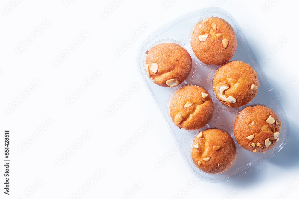 Freshly baked almond muffins in a transparent plastic tray on a white background. Freshly baked almond muffins in a transparent plastic tray on a white background.