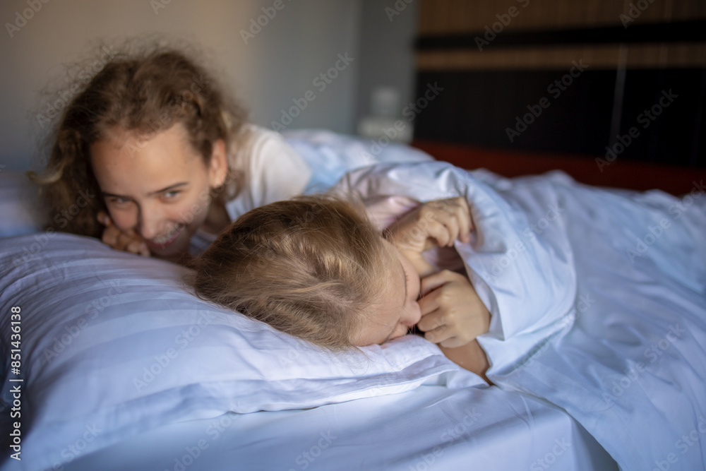 The laughter and joy of two blonde babies playing and fooling around on their big bed after a night of sleep. Children rub their eyes and try to wake up The laughter and joy of two blonde babies playing and fooling around on their big bed after a night of sleep. Children rub their eyes and try to wake up