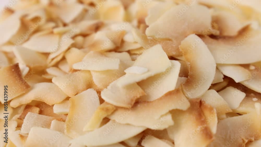 Thin sweet toasted coconut chips falling down close up Thin sweet toasted coconut chips falling down close up