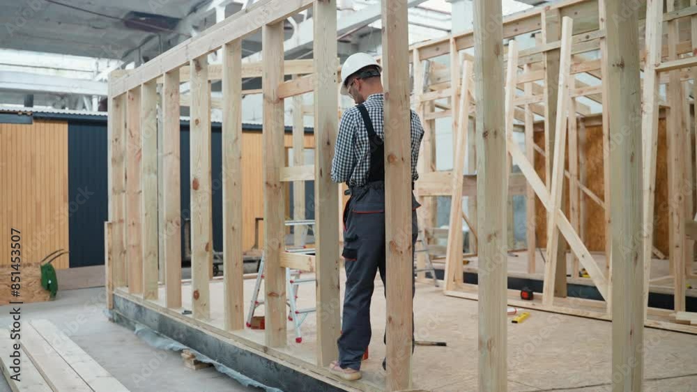 Worker carpenter assembling a modular house Worker carpenter assembling a modular house