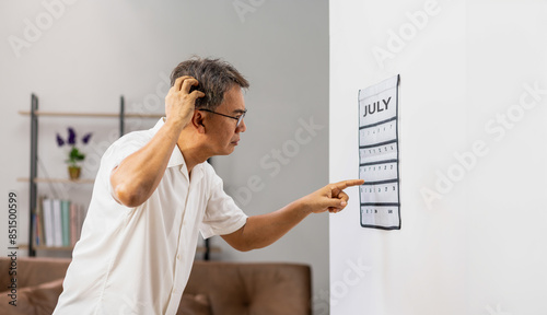Confused Asian Senior Man With Dementia Looking at Wall Calendar photo