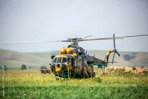 In the field is a military helicopter with soldiers. Armed conflict, fighting. Air armament and defense of the territory. photo