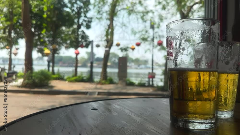 Two glasses of cold beer. Glass of beer on a wooden table. Traditional Bia Hoi Vietnamese beer over looking Truc Bach lake. Ha Noi, Vietnam.