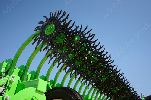 Close-up of a rotary harrow green color for processing an agricultural field. Against the background of the clean blue sky.
