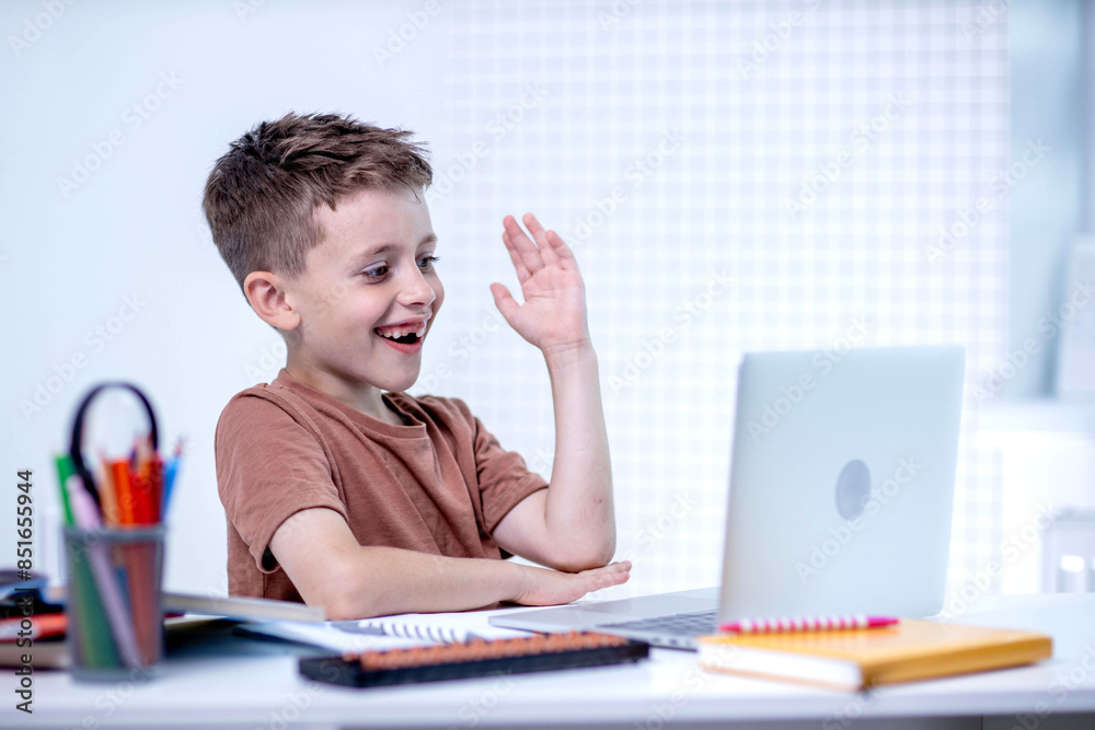 Schoolboy boy raises hand in online lesson at home Schoolboy boy raises hand in online lesson at home