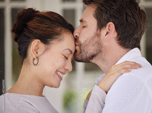 Love, happy and couple with kiss on forehead for care, bonding or affection at home together. Smile, marriage and sweet man embracing wife for romantic moment, loyalty or trust with joy in apartment.