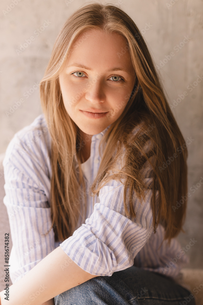 Portrait of blonde woman posing for portrait at cafe, sitting on comfortable armchair, looking with smile, sensual look at camera. Girl look sensual and dreaming wear shirt and jeans. Portrait of blonde woman posing for portrait at cafe, sitting on comfortable armchair, looking with smile, sensual look at camera. Girl look sensual and dreaming wear shirt and jeans.
