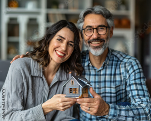 Cute couple buying a house and holding a miniature in their hands