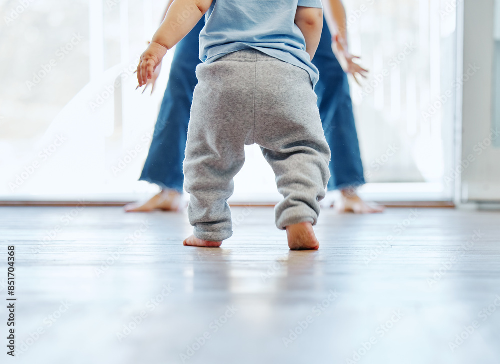 Back, baby and walking in home for development, motor skills and growth or first steps. Balance, parent and feet or legs in apartment for learning, love and trust or support together in morning Back, baby and walking in home for development, motor skills and growth or first steps. Balance, parent and feet or legs in apartment for learning, love and trust or support together in morning