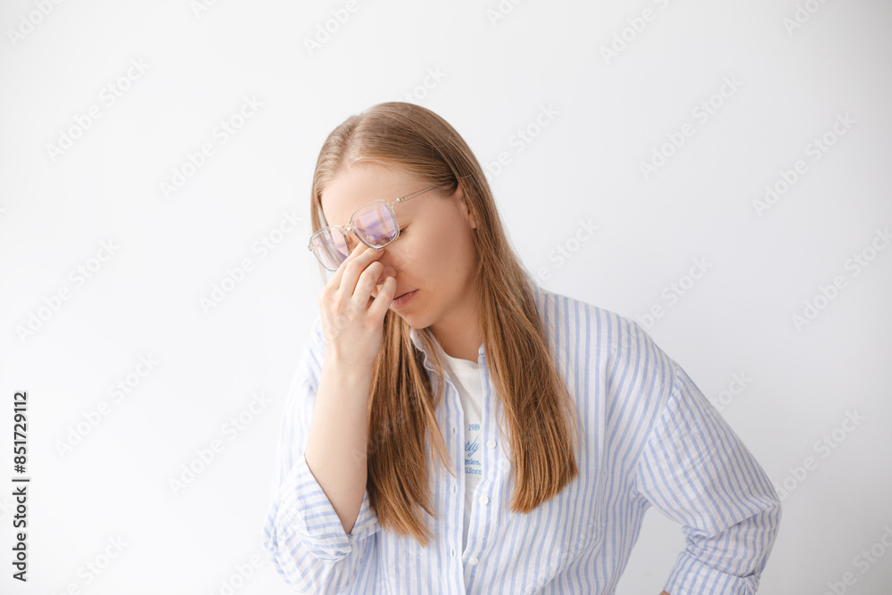 Tired blonde girl taking off glasses rubbing eyes isolated on white blank studio wall background, young fatigued woman feeling dry irritable eye strain, bad blurry vision problem tension. Tired blonde girl taking off glasses rubbing eyes isolated on white blank studio wall background, young fatigued woman feeling dry irritable eye strain, bad blurry vision problem tension.