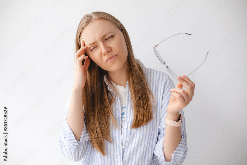 Upset young woman feeling eyestrain taking off glasses, tired girl holding eyeglasses suffer from headache massaging temple isolated on white studio background, eye fatigue strain migraine concept. Upset young woman feeling eyestrain taking off glasses, tired girl holding eyeglasses suffer from headache massaging temple isolated on white studio background, eye fatigue strain migraine concept.