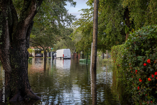 Wallpaper Mural After the 2024 Hallandale Beach flood, a car is submerged in floodwaters outside a suburban home. Reflections in the water emphasize the severe impact on residential areas and the need for recovery. Torontodigital.ca
