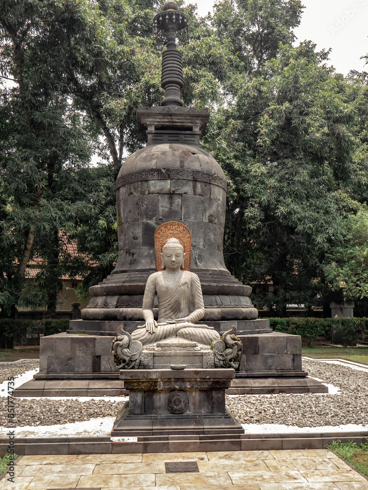 a Buddha sitting cross-legged on a lotus-shaped stone carving, complete with a stupa behind him
a Buddha sitting cross-legged on a lotus-shaped stone carving, complete with a stupa behind him