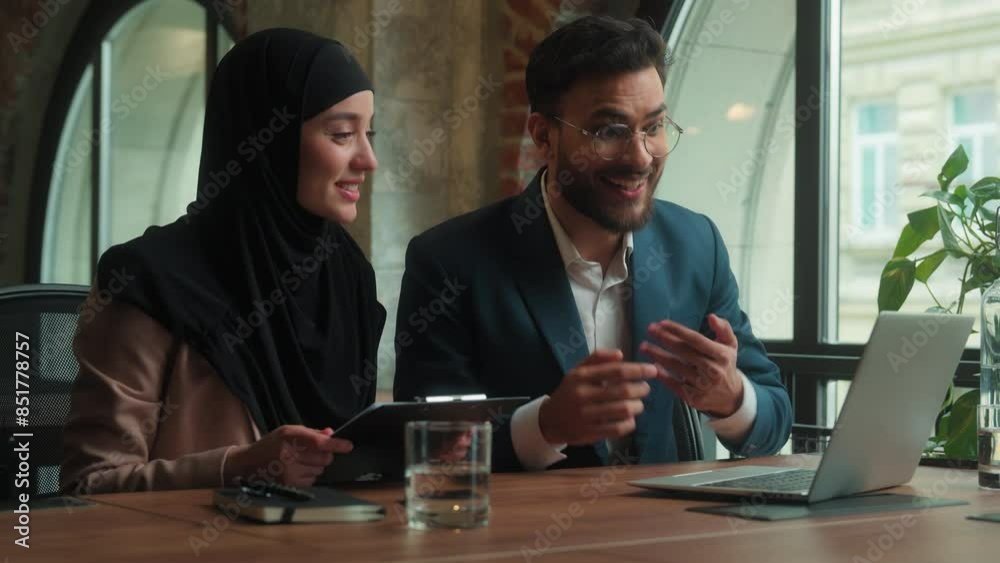 Arabian business colleagues two coworkers girl guy office employees male female muslim hijab woman man talk video call laptop online conference happy businessman businesswoman showing financial graph Arabian business colleagues two coworkers girl guy office employees male female muslim hijab woman man talk video call laptop online conference happy businessman businesswoman showing financial graph