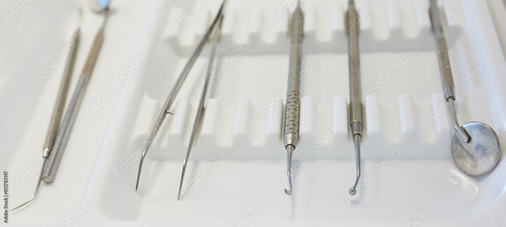 Closeup, metal and dental tools for healthcare with excavator and instrument layout for teeth cleaning. Oral hygiene, dentistry equipment and setup for tooth wellness, mouth procedure and treatment Closeup, metal and dental tools for healthcare with excavator and instrument layout for teeth cleaning. Oral hygiene, dentistry equipment and setup for tooth wellness, mouth procedure and treatment