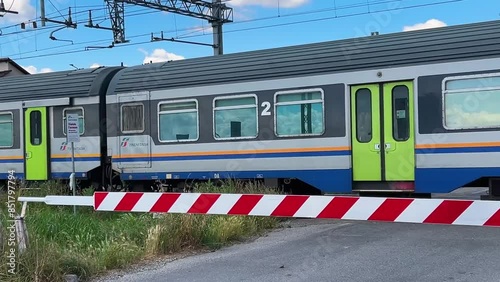 Cavallermaggiore, Italy - June 15, 2024: Trenitalia train passing at the level crossing on the railway line between Turin and Savona photo