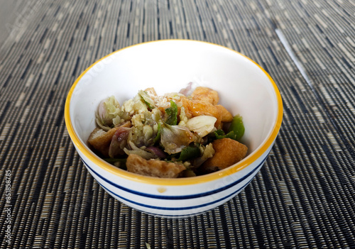 Delicious Tahu Gejrot Dish in a White Bowl on Blue Textured Background with Crispy Tofu and Spicy Sweet Sauce, Indonesian Cuisine Close up photo