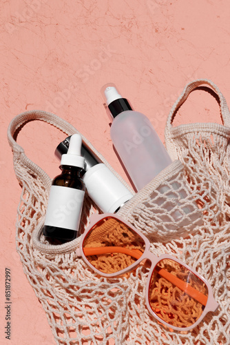 Skincare bottle mockup styled with a mesh tote and orange-colored sunglasses in sunlight
